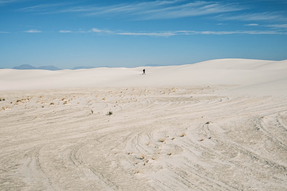 person walking on white sand during daytime