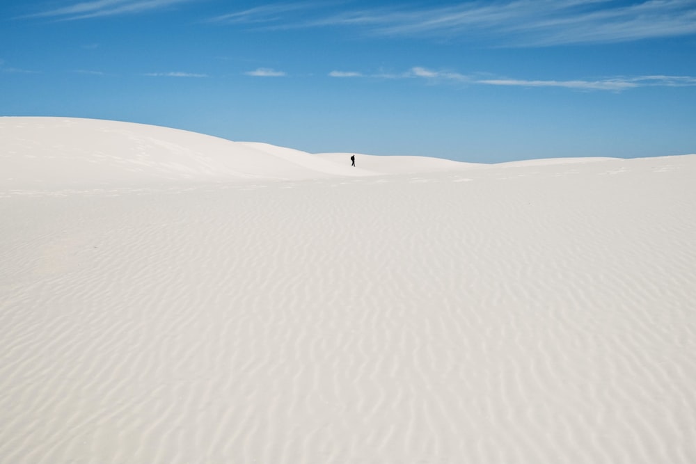 person walking on white sand during daytime