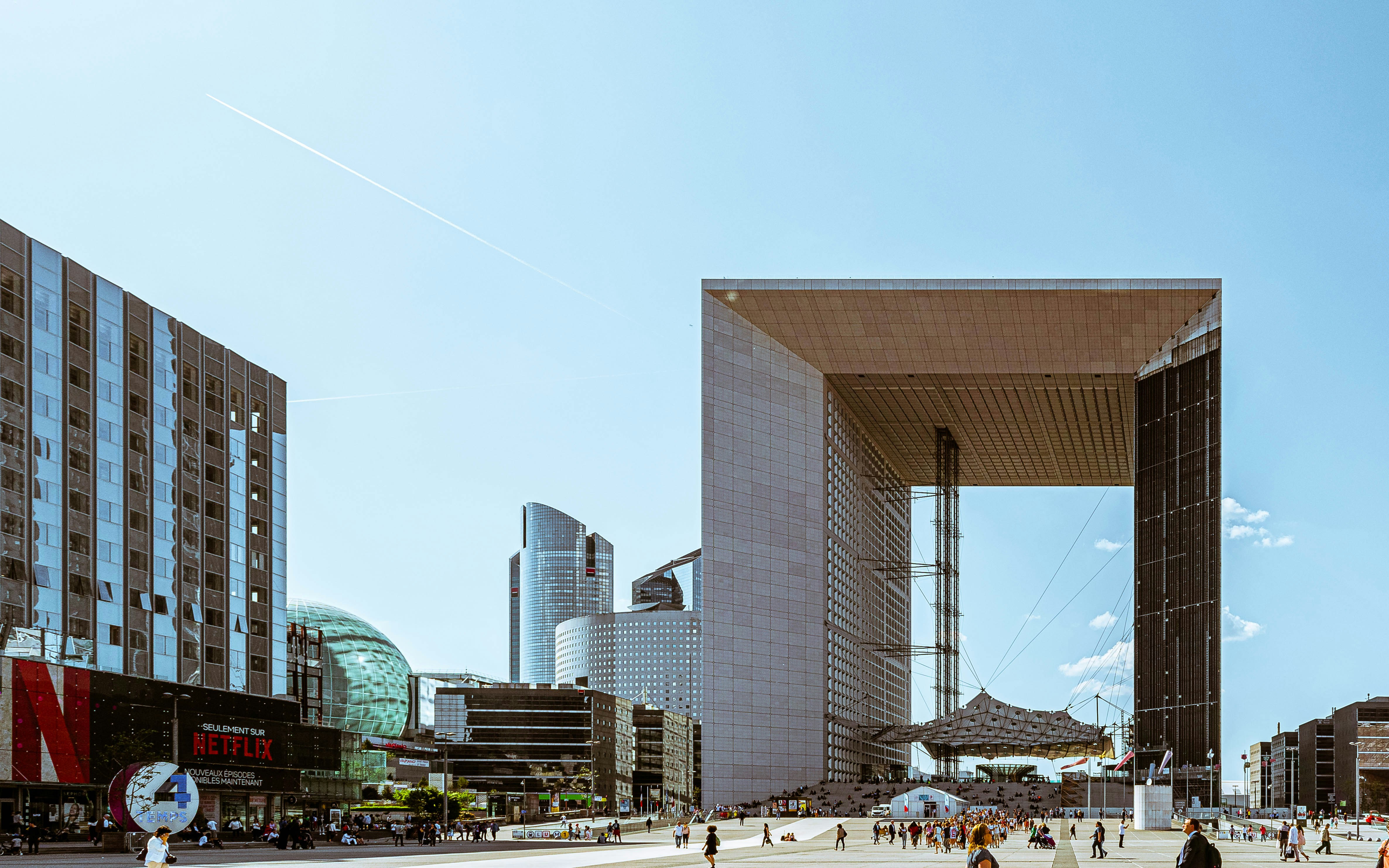 white and brown concrete building during daytime, The Grand Arch in Paris, France on Public Plaza surrounded by commercial buildings