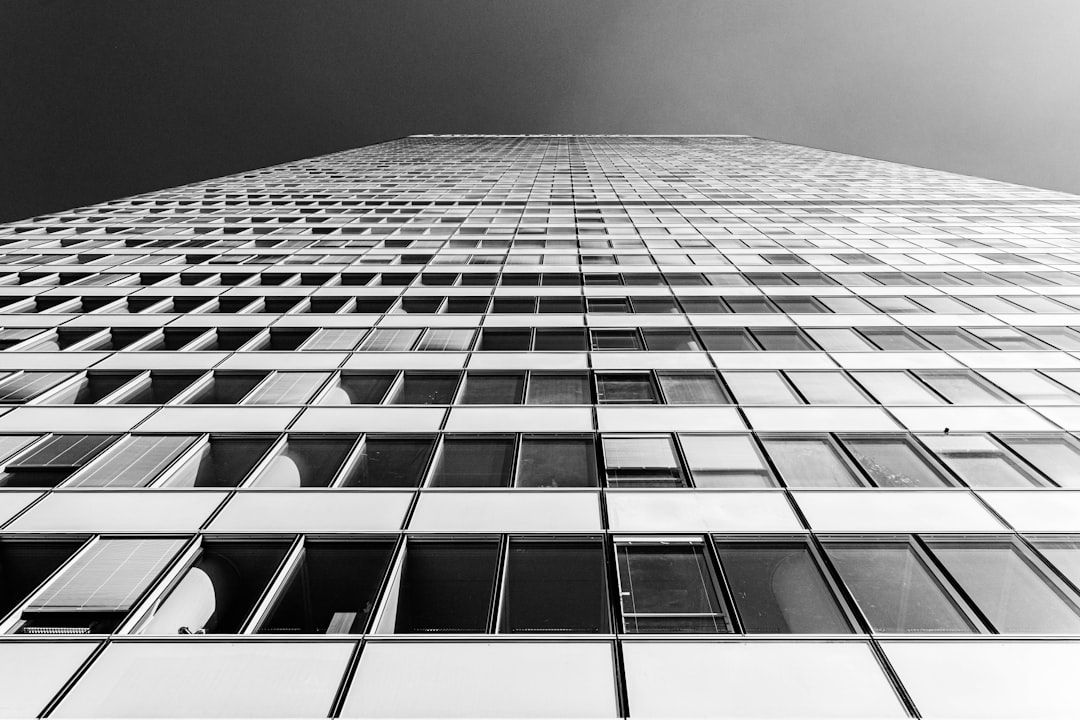 grayscale photo of high rise building, Glass Curtain Wall facade with glazing looking up of Commercial building in Paris