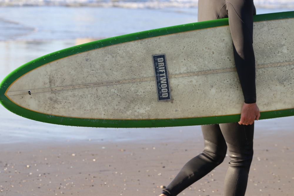 person holding green and white surfboard
