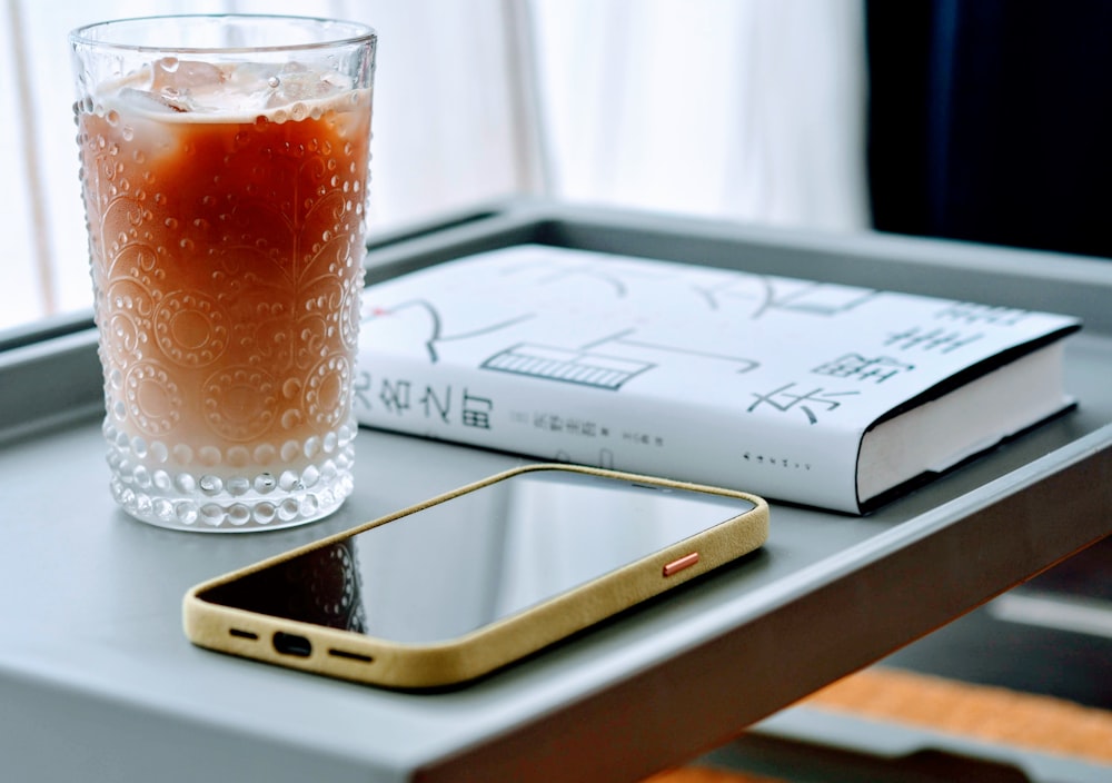 clear drinking glass with brown liquid on white paper