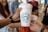 A group of people holding white coffee cups with a blue logo that reads 'Coffee Call Start a Tradition.' Some individuals are slightly blurred in the background, suggesting a social and casual setting.