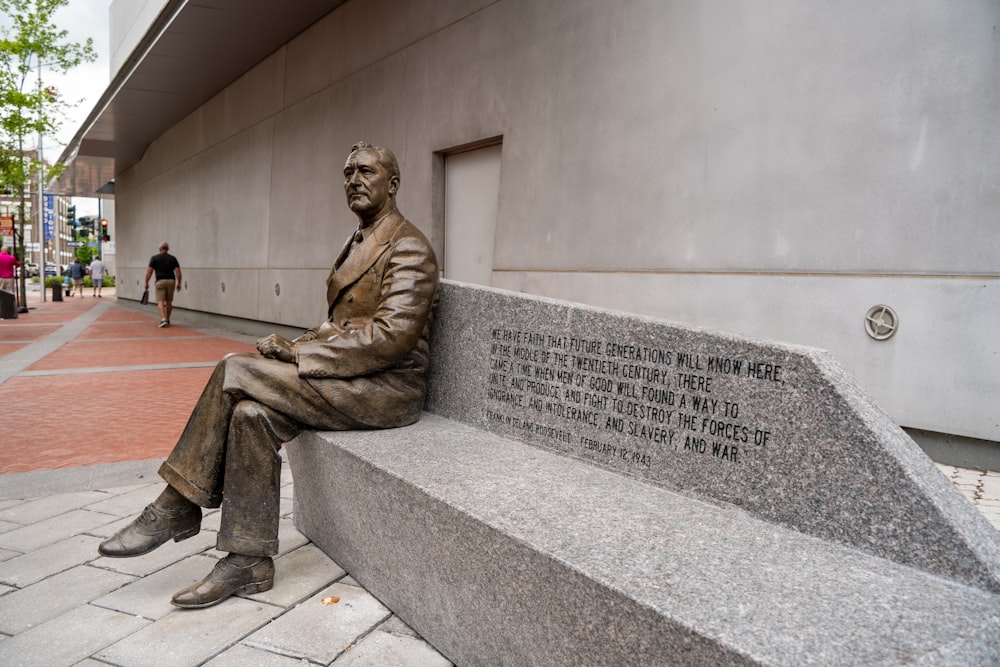 man in brown coat sitting on concrete bench