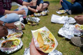 Happy group of friends sharing tacos at an outdoor food truck event in Houston.