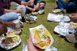 Happy group of friends sharing tacos at an outdoor food truck event in Houston.