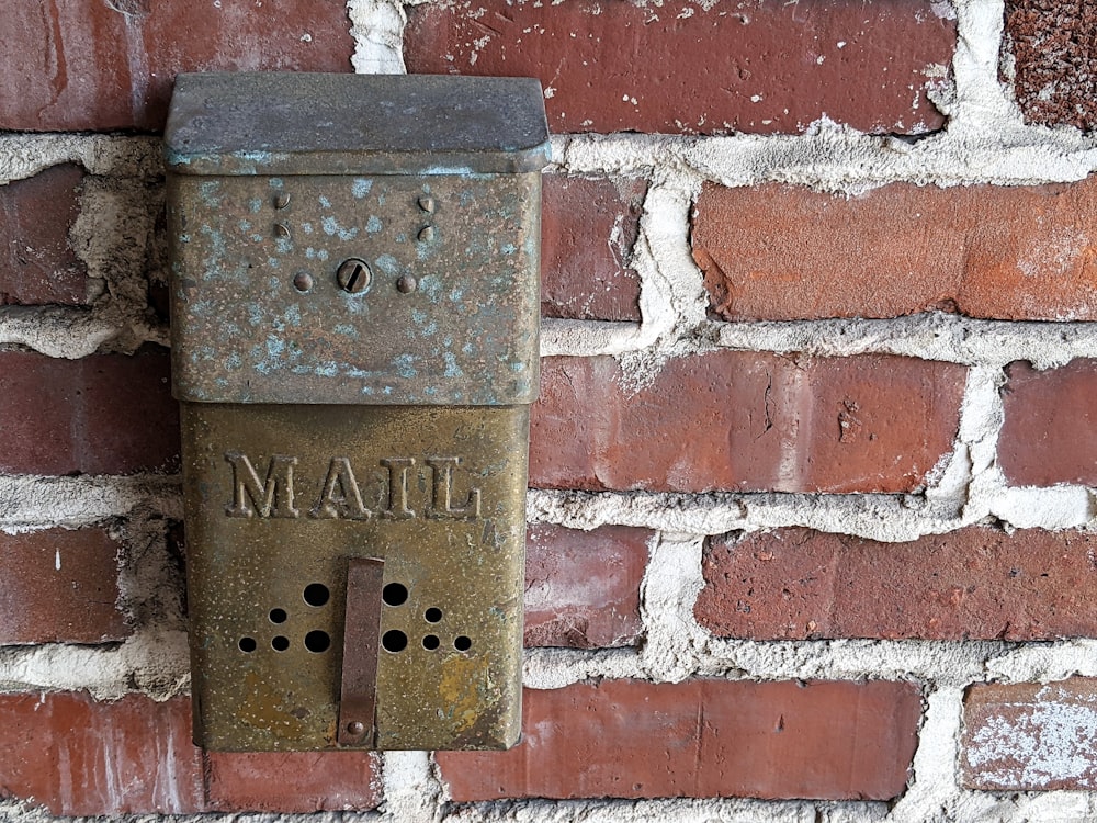 Boîte aux lettres en métal brun montée sur un mur de briques rouges