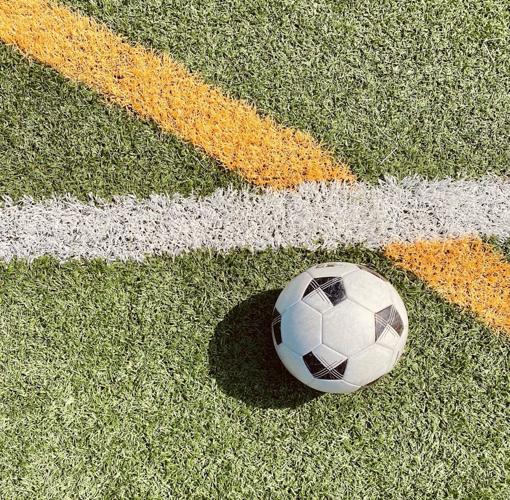 white and black soccer ball on green grass field
