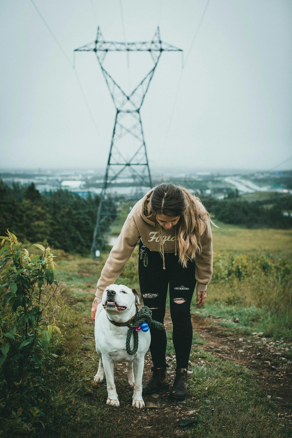 woman in black jacket holding white short coated dog