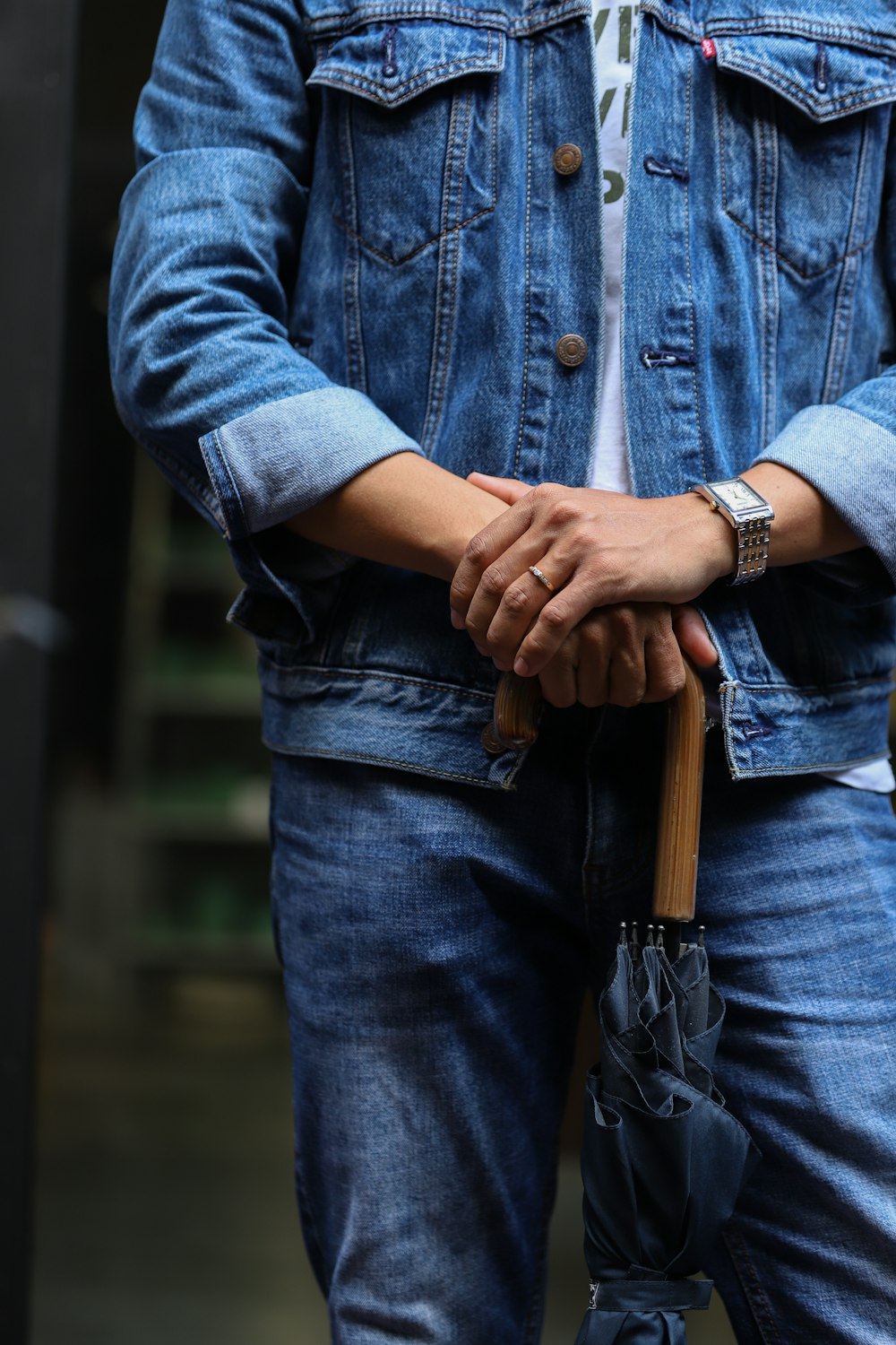 person in blue denim jacket and blue denim jeans holding brown wooden stick