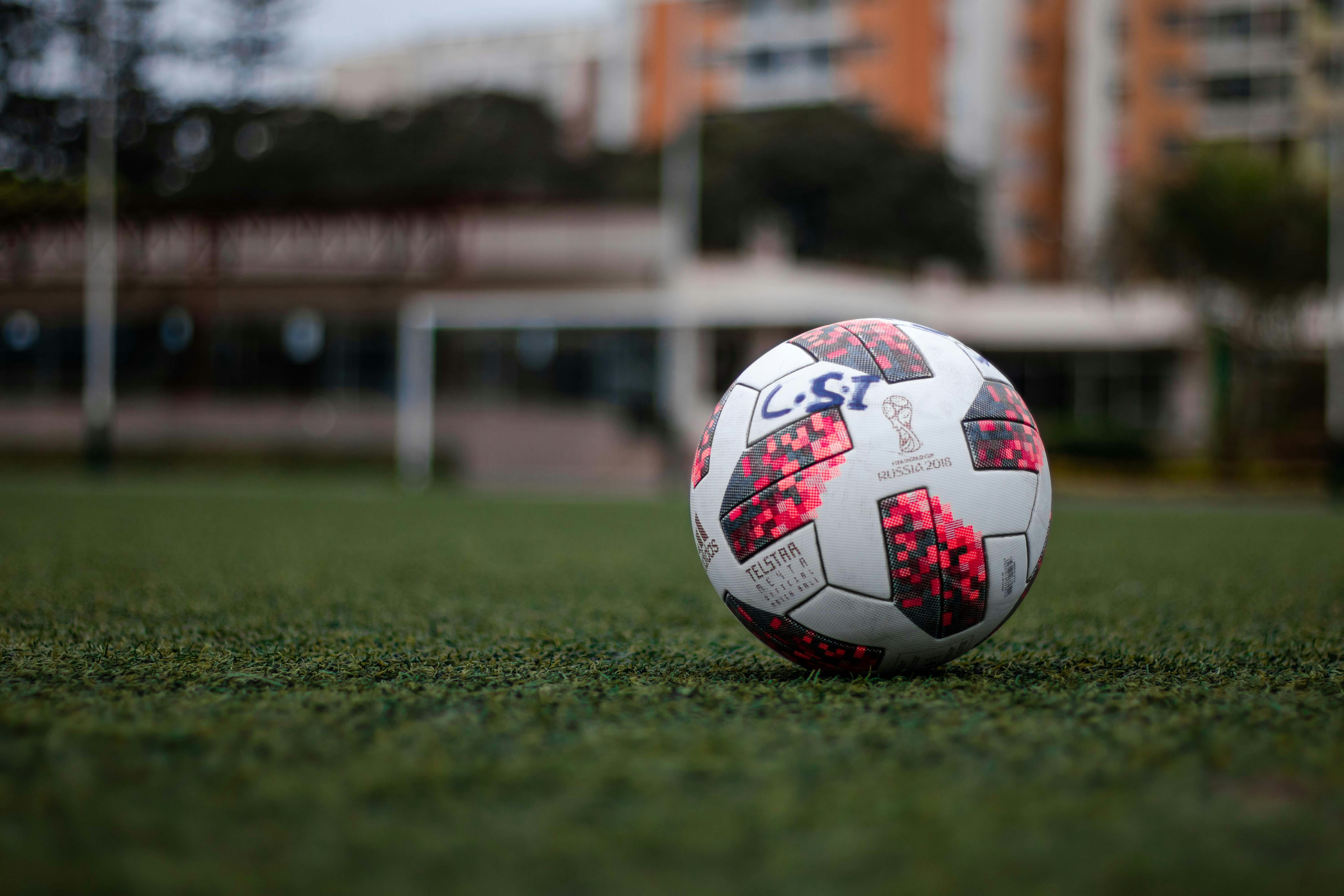 white red and blue soccer ball on green grass field during daytime