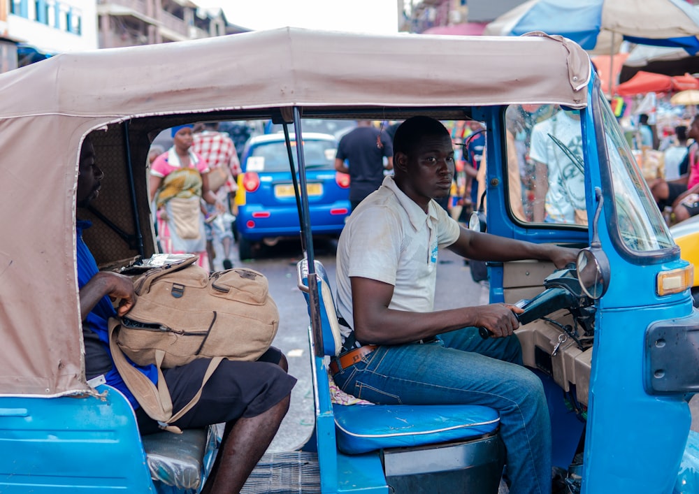 man in white t-shirt and blue denim jeans sitting on blue car seat