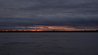body of water under cloudy sky during sunset