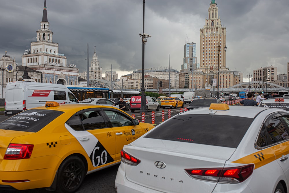 white and yellow taxi cab on road near city buildings during daytime