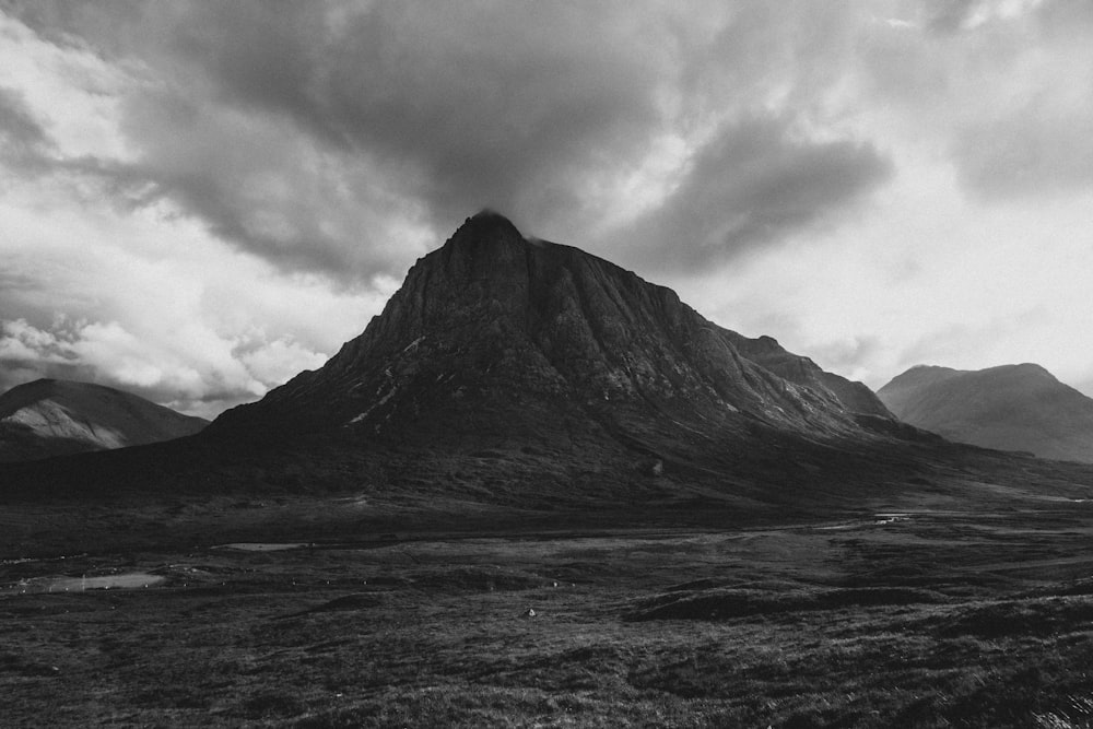 grayscale photo of mountain under cloudy sky