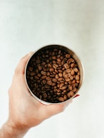Hands holding a sol coffee pack with a backdrop of sunlit coffee beans scattered around.