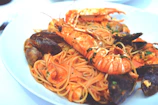 A vibrant seafood pasta with shrimp and mussels in a tomato-based sauce, garnished with parsley