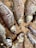 Several dried fish laid out on a woven bamboo mat. The fish appear desiccated, showing visible rib structures and sunken eyes. The earthy tones of the bamboo complement the muted, brownish hues of the fish scales.