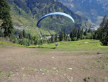 A paramotor pilot soaring above a colorful village at sunrise.