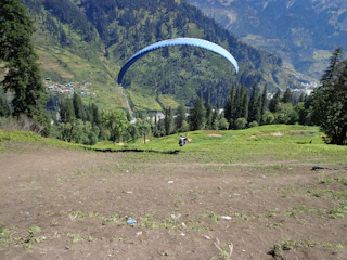 A paramotor pilot soaring gently over a vibrant village, capturing breathtaking aerial footage.