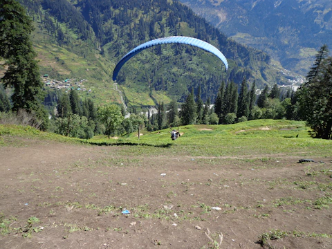 A paramotor pilot soaring above a colorful village at sunrise.