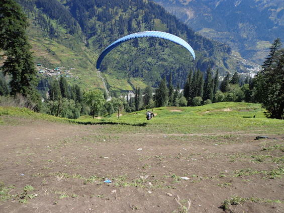 A paramotor pilot soaring gently over a vibrant village, capturing breathtaking aerial footage.