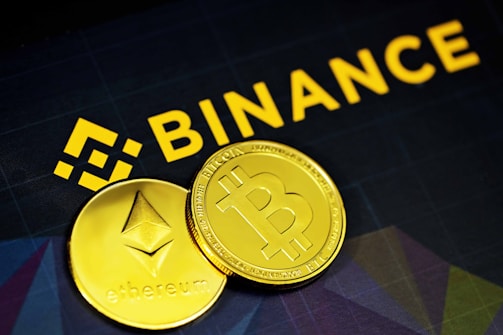 two gold bitcoins sitting next to a binance sign