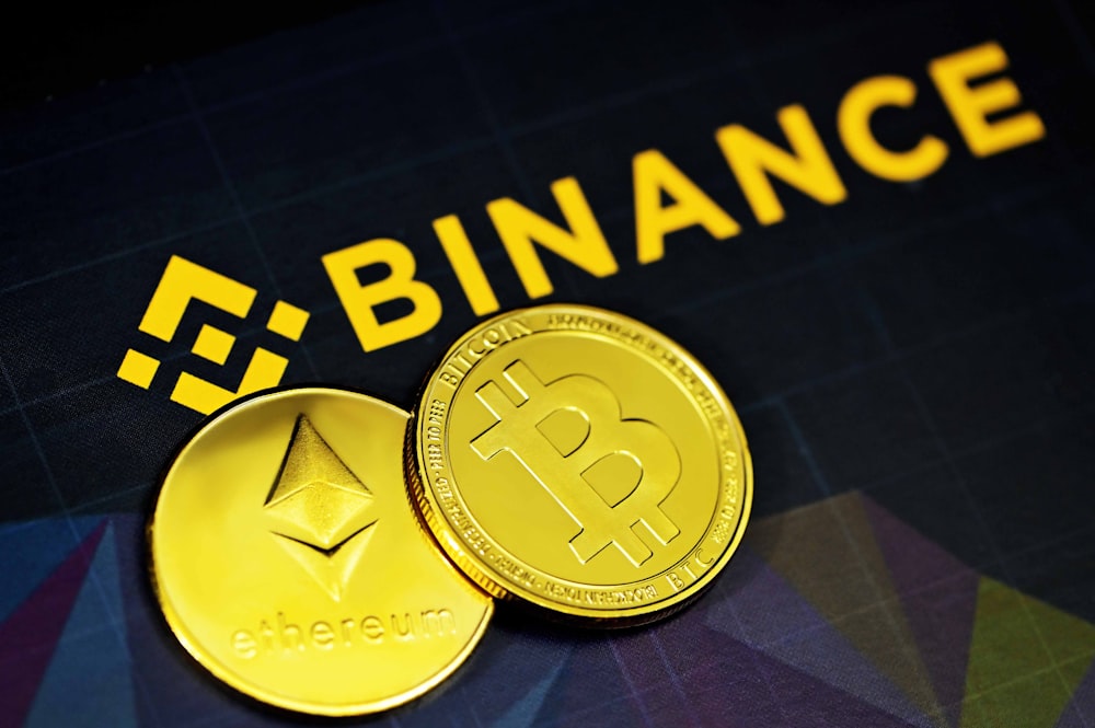 Dos bitcoins de oro sentados junto a un letrero de Binance