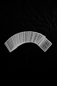 Bridge cards fanned out on a deep red velvet cloth with ancient Roman motifs.
