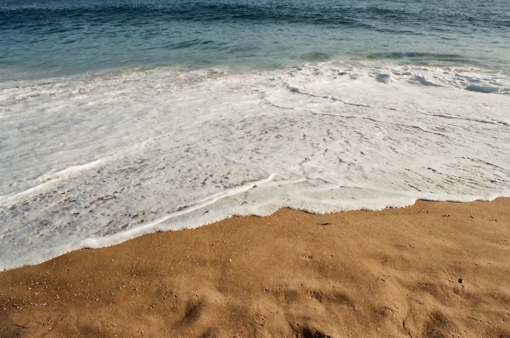 brown sand near body of water during daytime