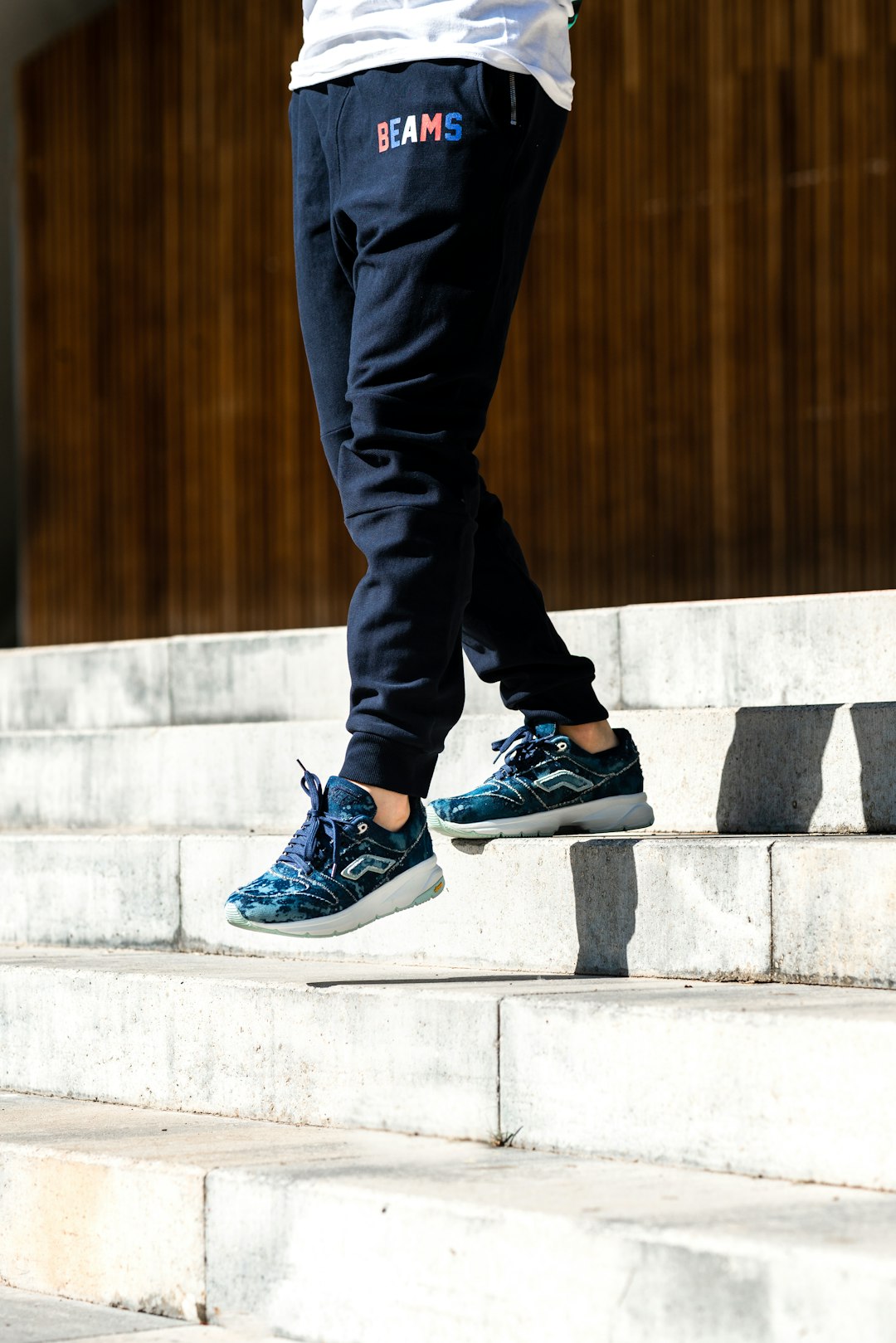 person in black pants and black and white nike sneakers standing on gray concrete stairs