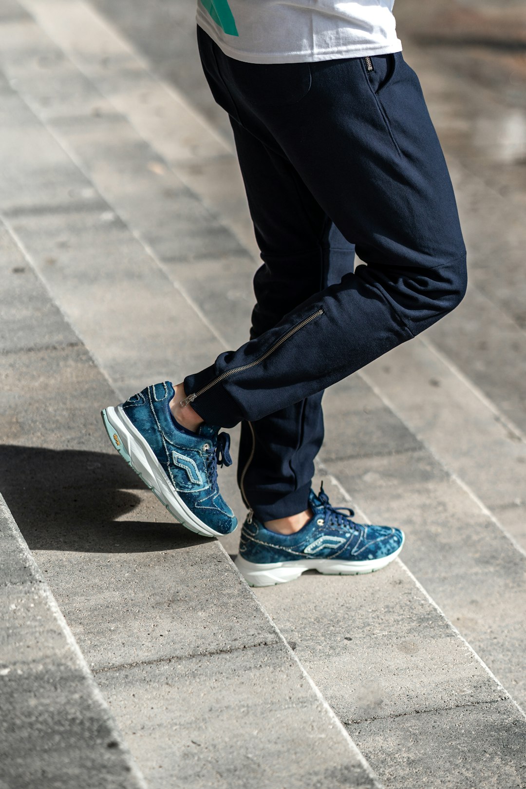 person in black pants wearing blue and white nike sneakers