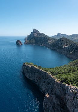 green grass covered mountain beside blue sea during daytime