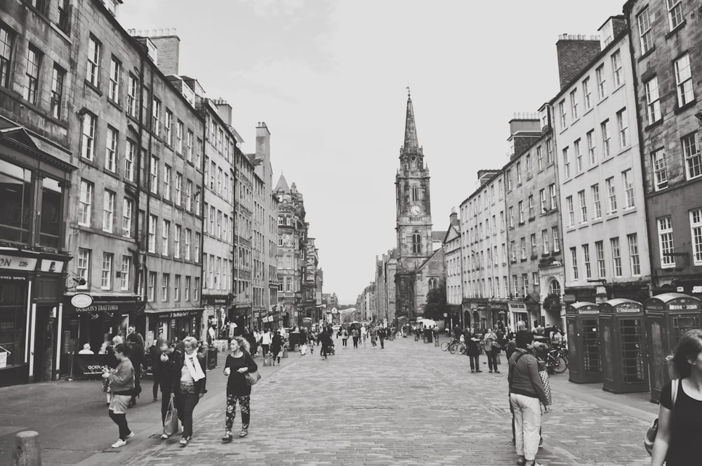 grayscale photo of people walking on street near buildings