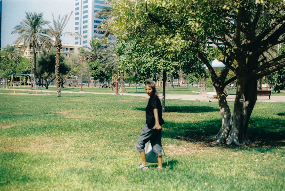 woman in black dress standing on green grass field during daytime