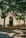 An ornate entrance labeled 'Casal de S. Pedro', adorned with a decorative archway and tiled details. It is surrounded by lush green trees casting shadows on the cobblestone pathway with benches placed alongside.