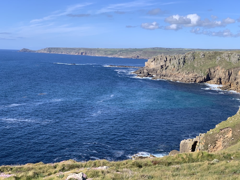 Formación rocosa gris cerca del mar azul bajo el cielo azul durante el día