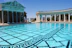 A sparkling newly resurfaced pool with clear blue water reflecting the sky, surrounded by elegant paving.