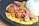A plate of food featuring creamy curry sauce with diced vegetables, golden-brown fried chicken pieces, and strips of seared meat. On the side, there is a portion of steamed white rice topped with black sesame seeds. The dish is artistically plated on a dark, round plate.