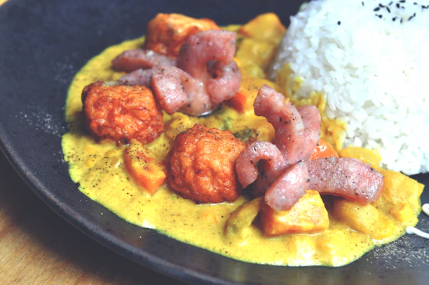 A vibrant close-up of a sizzling South Asian curry alongside a crispy continental fried chicken.