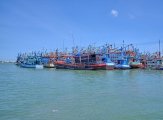Colorful fishing boats docked in Essaouira’s old harbor under a bright blue sky.