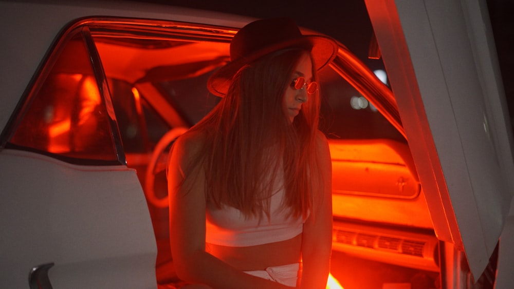 woman in white tank top and brown fedora hat sitting on car seat