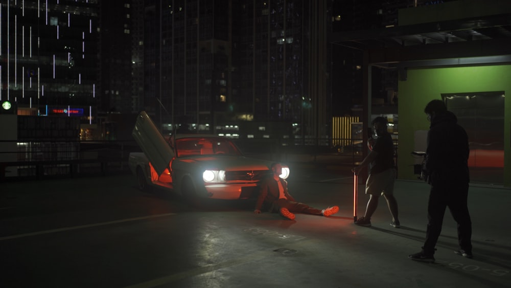 man in black jacket and pants standing on sidewalk during night time