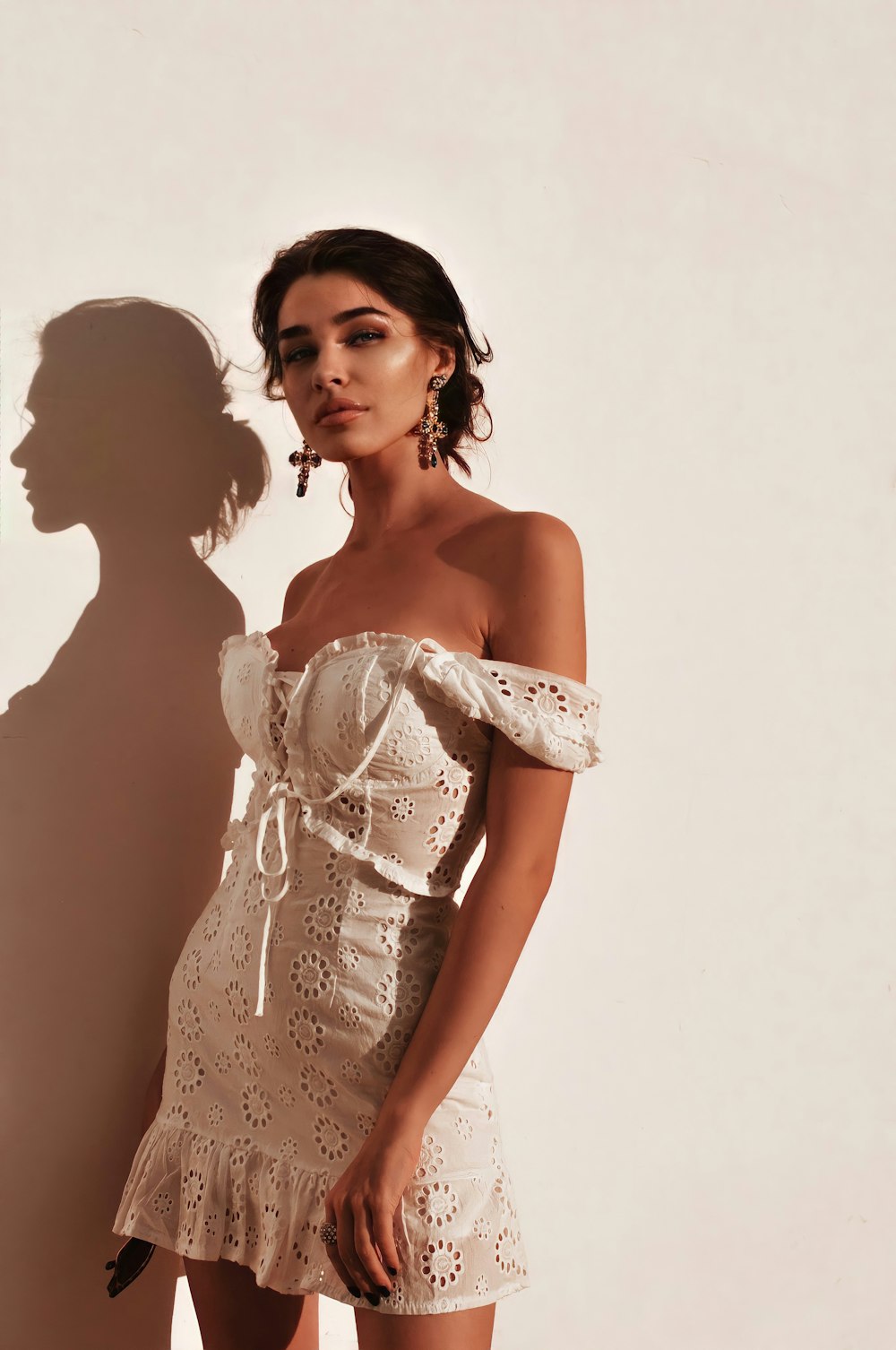 a woman in a white dress standing next to a wall