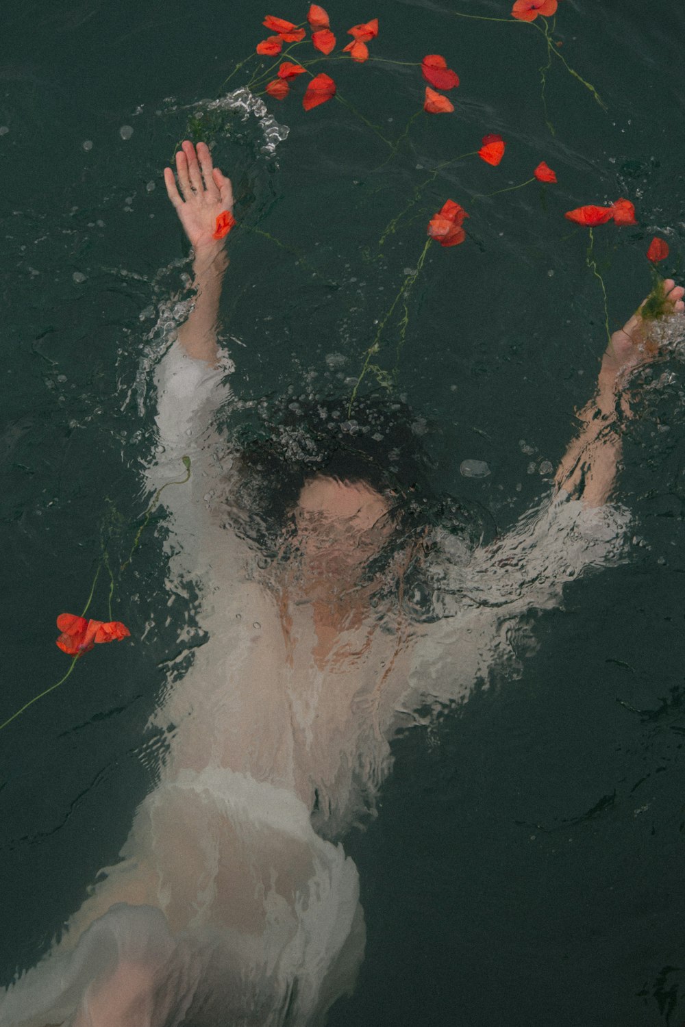 femme dans l’eau avec des pétales rouges