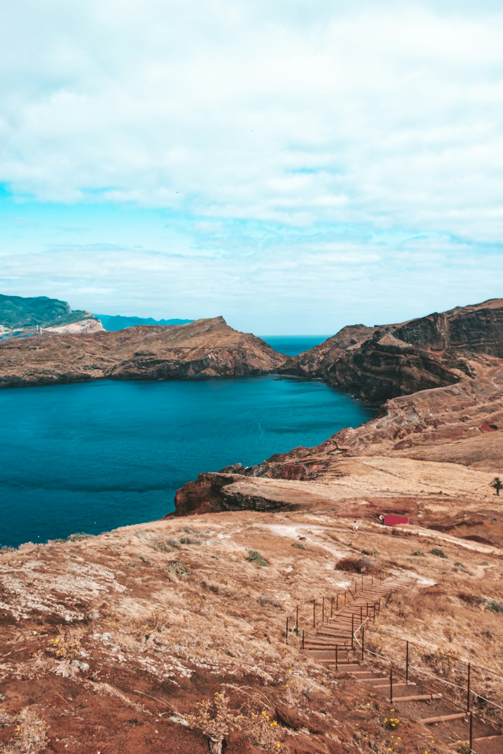 Brauner felsiger Berg neben blauem Meer unter blauem Himmel tagsüber