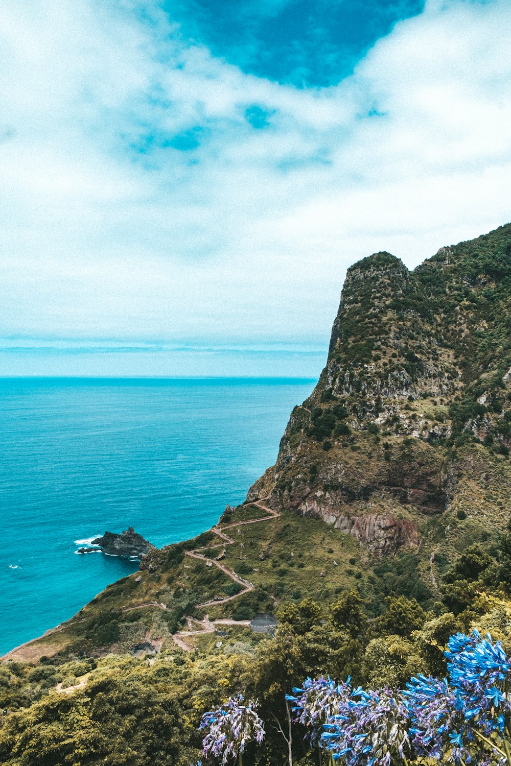 green and brown rock formation beside blue sea under blue sky during daytime