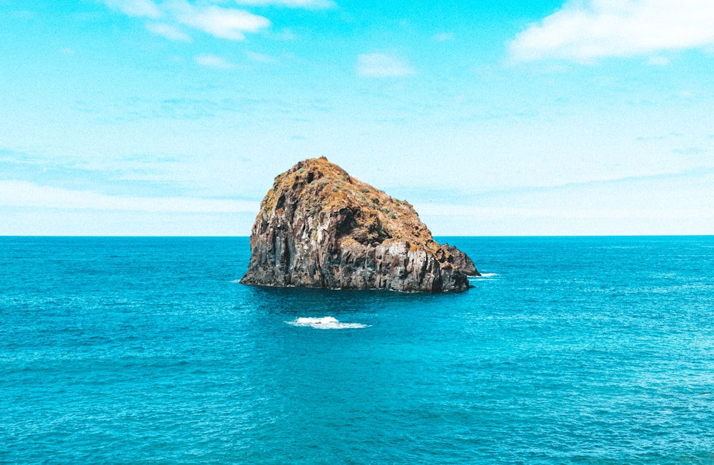 brown rock formation on blue sea under blue sky during daytime