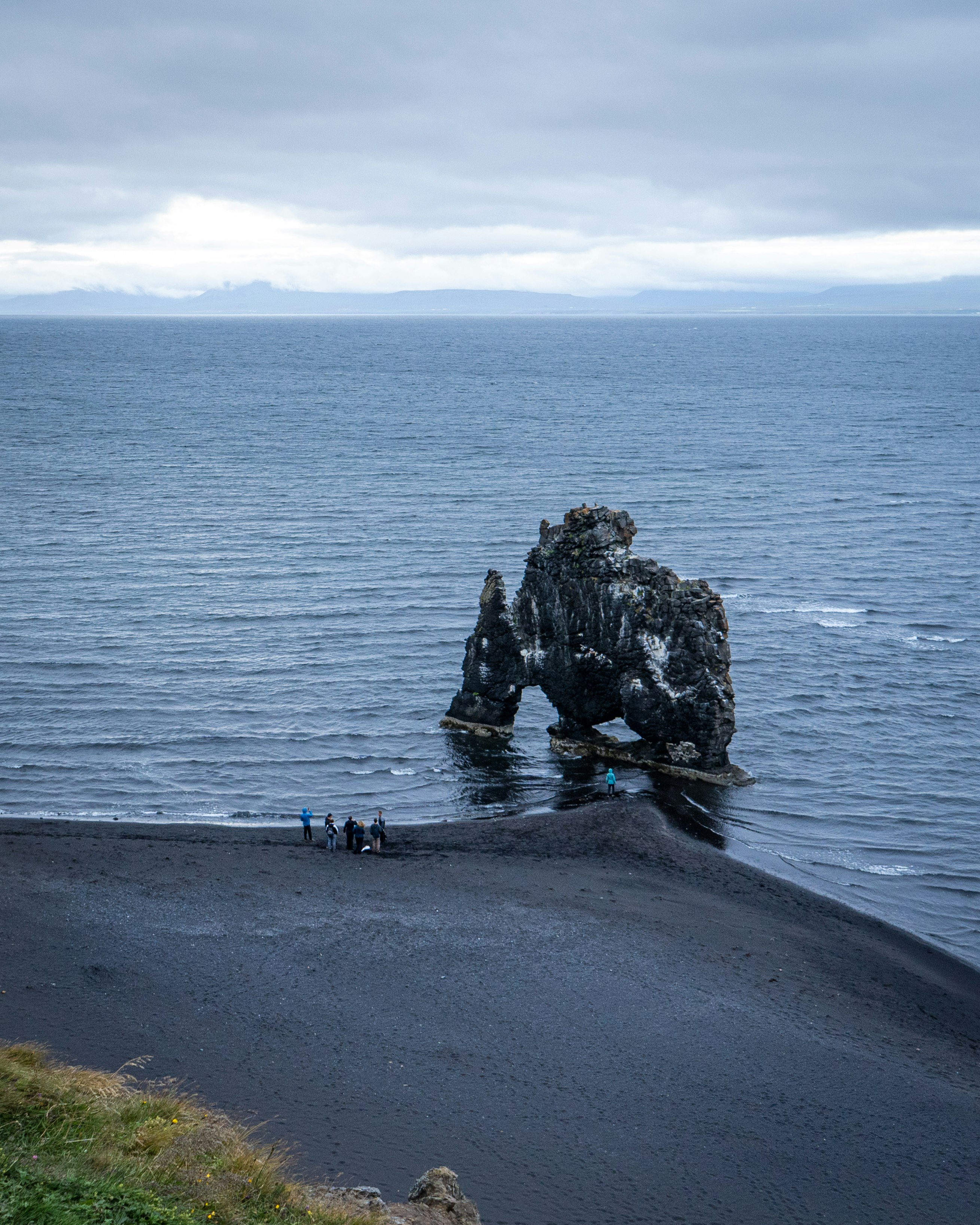 people walking on gray concrete road near body of water during daytime