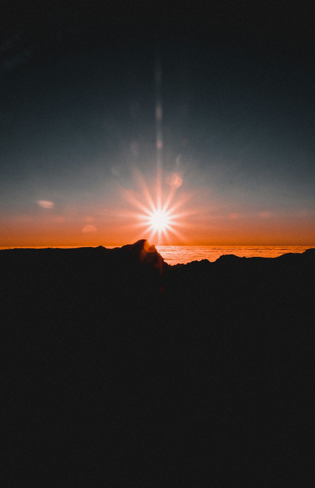 silhouette of person standing on mountain during sunset